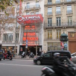 A street scene in Paris. Note the kiosk on the right side, which seem to be ubiquitous in Europe.