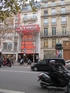 A street scene in Paris. Note the kiosk on the right side, which seem to be ubiquitous in Europe.