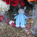 A mourner left a rabbit among the flowers, candles, and signs.