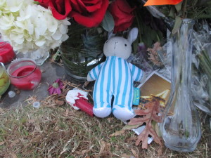 A mourner left a rabbit among the flowers, candles, and signs.